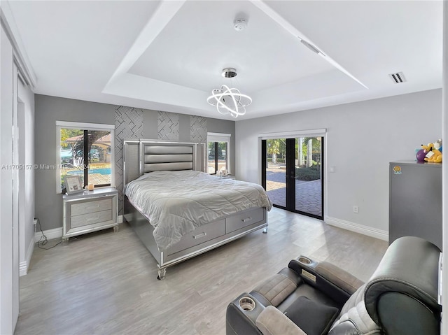 bedroom with visible vents, access to exterior, baseboards, a chandelier, and a tray ceiling