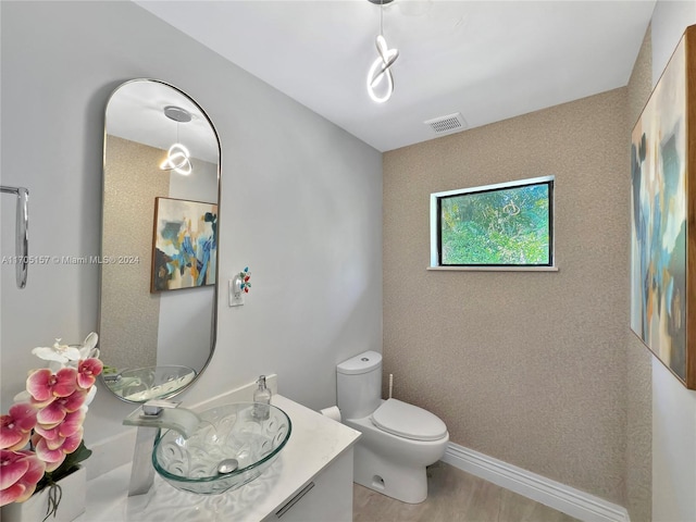 bathroom featuring visible vents, wood finished floors, toilet, and vanity