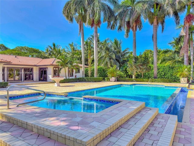 view of swimming pool featuring french doors, a patio, and a pool with connected hot tub