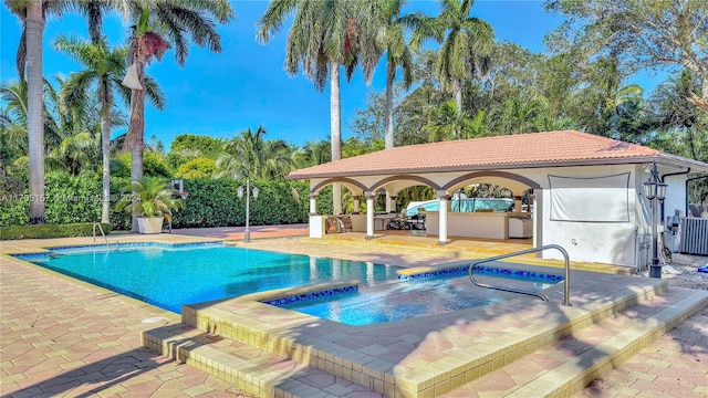 outdoor pool featuring a patio and an in ground hot tub
