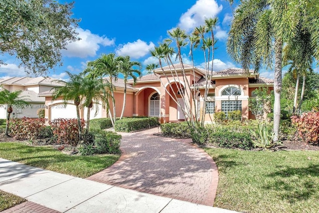 mediterranean / spanish-style home featuring a front yard and a garage