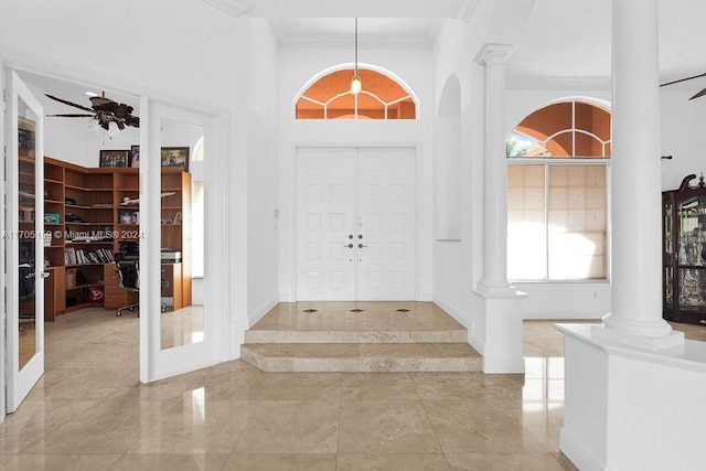 foyer with ornamental molding, a towering ceiling, ceiling fan, and a healthy amount of sunlight