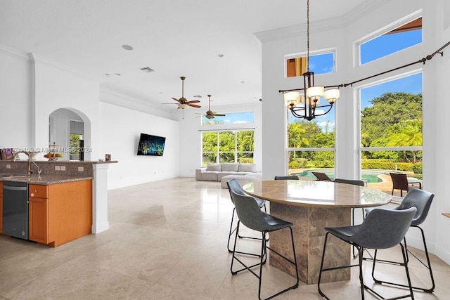 tiled dining space featuring sink, ceiling fan with notable chandelier, and ornamental molding