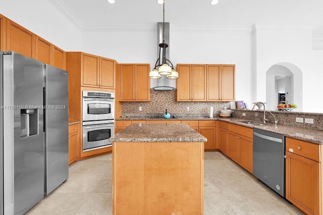 kitchen featuring ornamental molding, stainless steel appliances, sink, a kitchen island, and hanging light fixtures