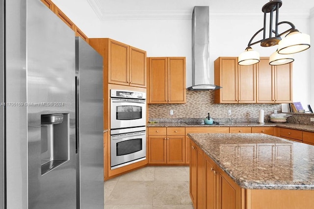 kitchen featuring dark stone counters, a center island, stainless steel appliances, and wall chimney range hood