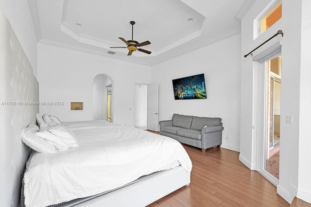 bedroom featuring ceiling fan, wood-type flooring, ornamental molding, and a tray ceiling