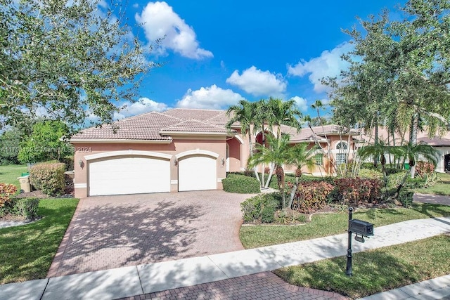 mediterranean / spanish house with a garage and a front lawn