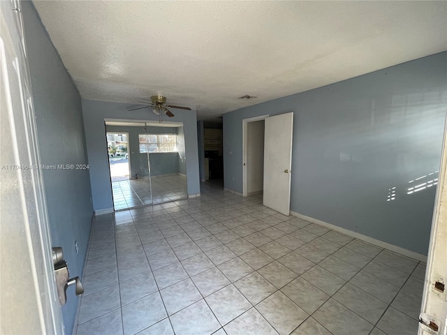 tiled spare room with ceiling fan and a textured ceiling