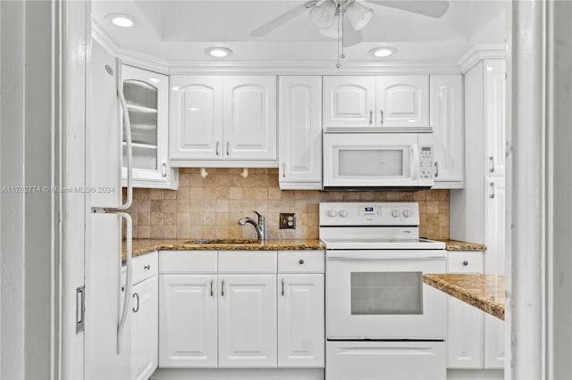 kitchen featuring dark stone countertops, sink, white cabinets, and white appliances