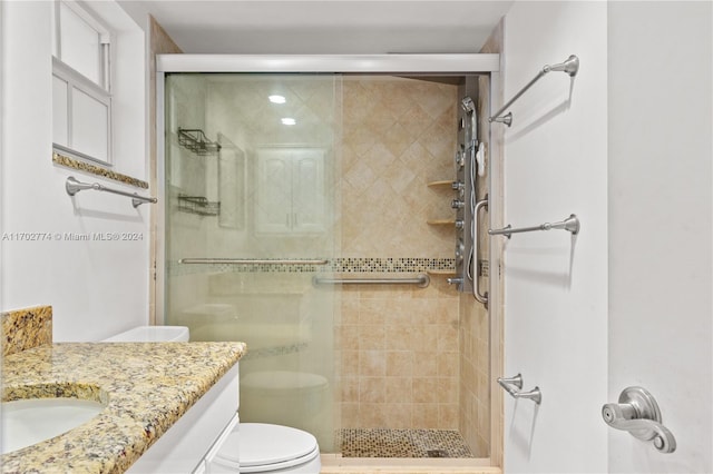 bathroom with walk in shower, vanity, and toilet