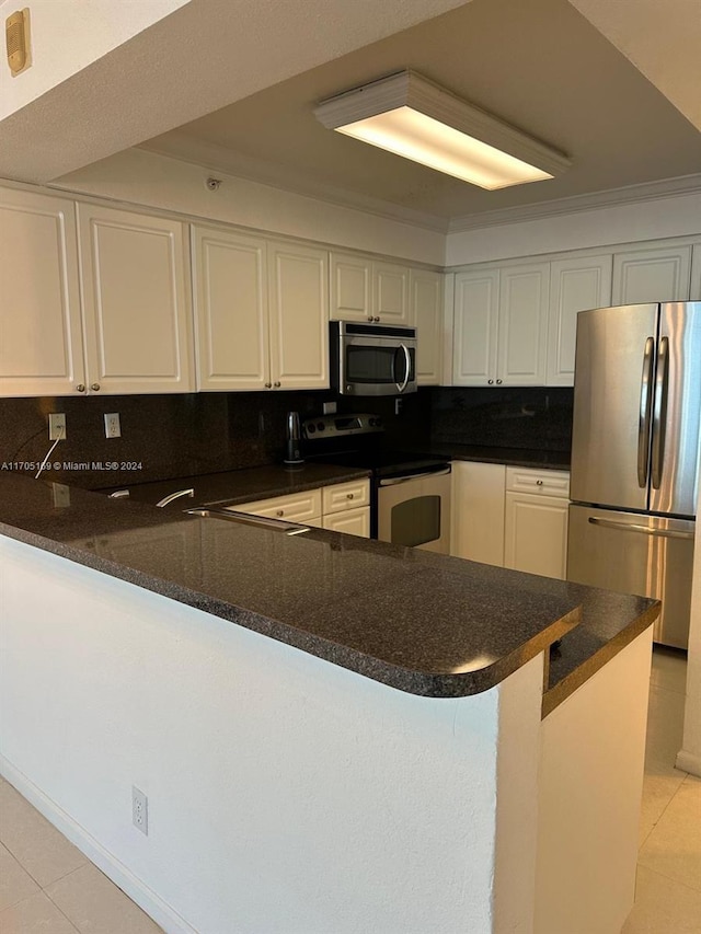 kitchen with kitchen peninsula, appliances with stainless steel finishes, decorative backsplash, ornamental molding, and white cabinets