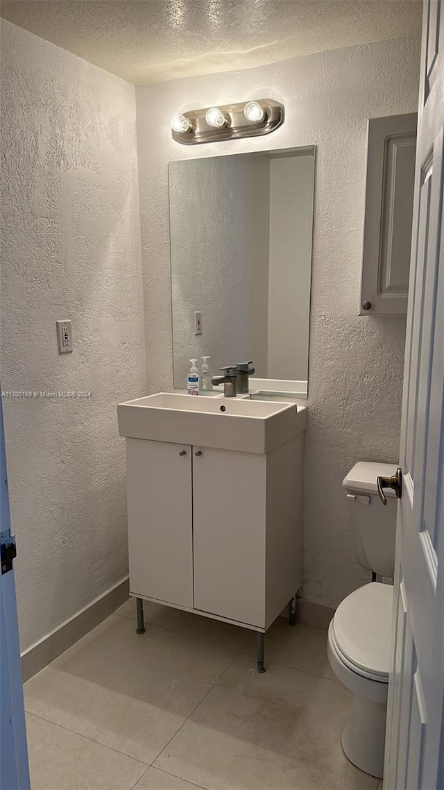 bathroom with tile patterned floors, vanity, a textured ceiling, and toilet