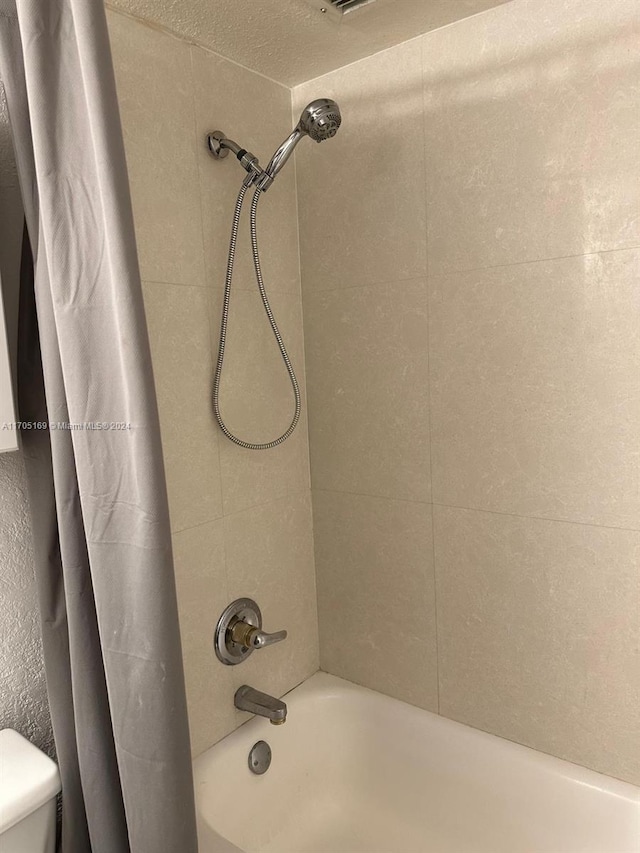 bathroom with shower / bath combination with curtain and toilet