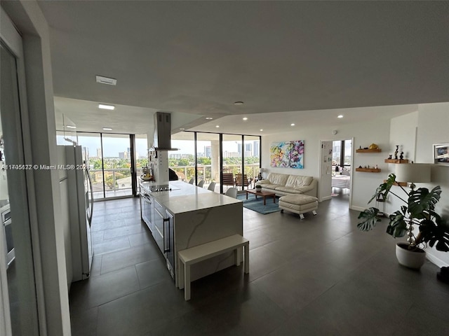 kitchen featuring stainless steel refrigerator, light stone countertops, plenty of natural light, and a wall of windows