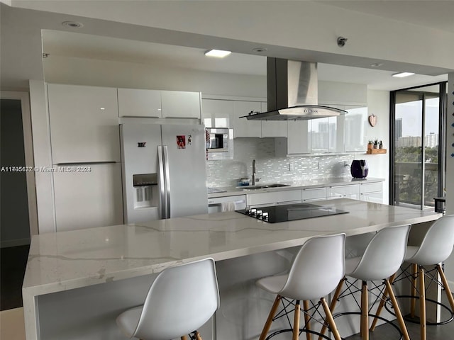 kitchen featuring sink, stainless steel appliances, backsplash, island exhaust hood, and white cabinets