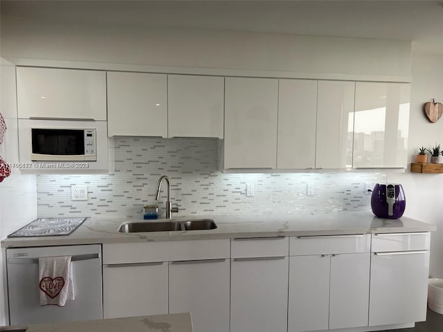 kitchen featuring decorative backsplash, dishwasher, white cabinets, and sink