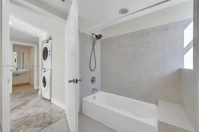 bathroom featuring stacked washer and dryer, tiled shower / bath combo, and sink