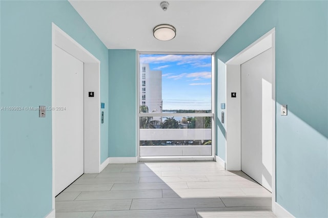 hall with elevator, light hardwood / wood-style flooring, and expansive windows