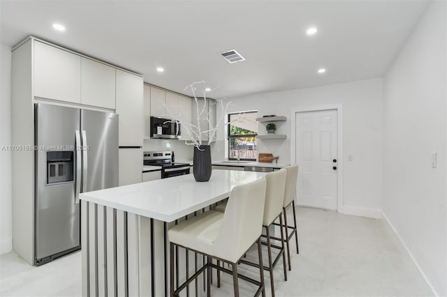 kitchen with sink, a center island, a breakfast bar area, white cabinets, and appliances with stainless steel finishes