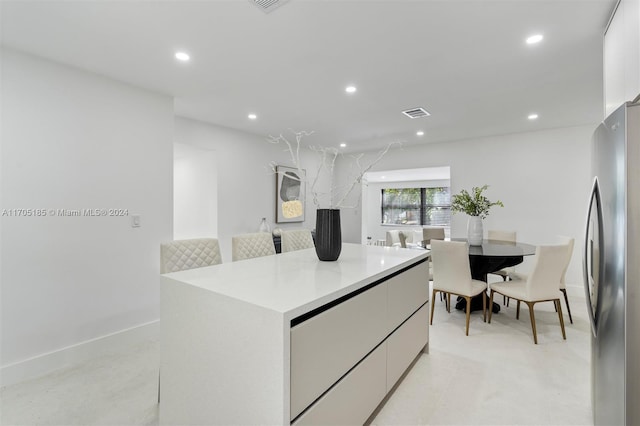 kitchen with white cabinets, stainless steel fridge, and a kitchen island