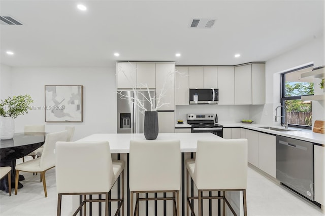 kitchen with appliances with stainless steel finishes, a kitchen island, a breakfast bar area, and sink