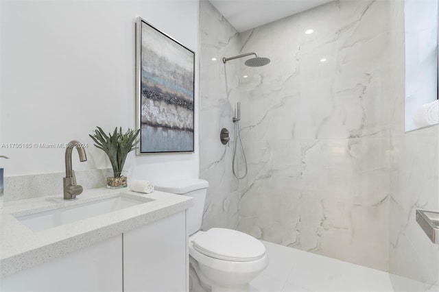 bathroom with tiled shower, vanity, and toilet