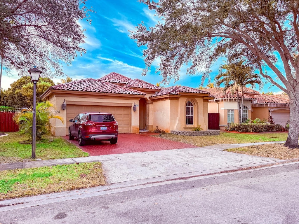 mediterranean / spanish-style home featuring a front yard and a garage