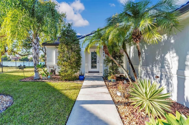 view of exterior entry with a yard and a water view