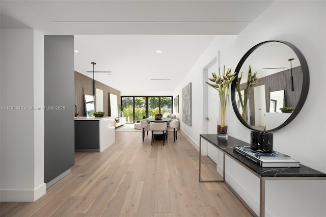 corridor featuring light wood finished floors and baseboards