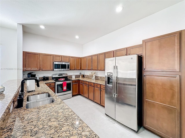 kitchen with light stone countertops, appliances with stainless steel finishes, and sink