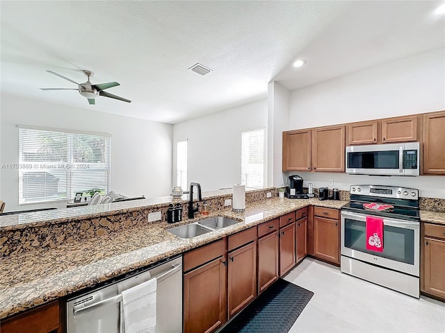 kitchen with a wealth of natural light, sink, light stone countertops, and appliances with stainless steel finishes