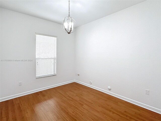 spare room with a chandelier, plenty of natural light, and hardwood / wood-style floors