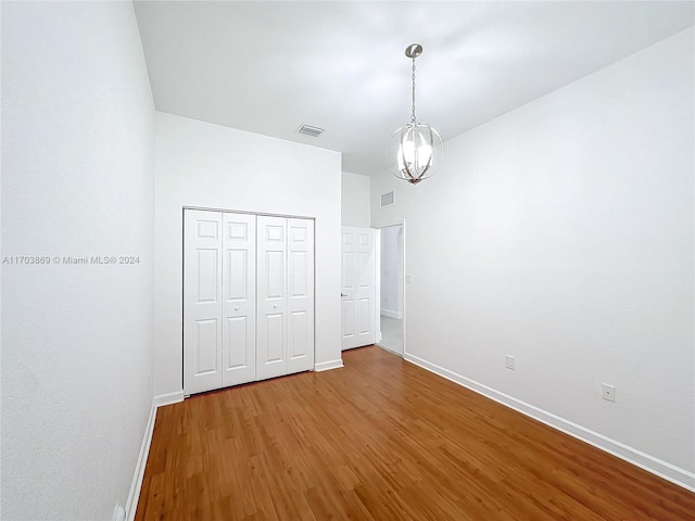 unfurnished bedroom with hardwood / wood-style flooring, a closet, and a notable chandelier