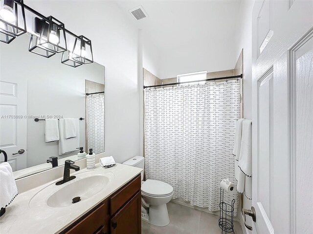 bathroom featuring tile patterned flooring, vanity, curtained shower, and toilet