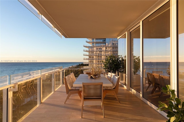 balcony at dusk featuring a water view