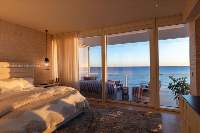 bedroom featuring access to exterior, wood-type flooring, and a water view