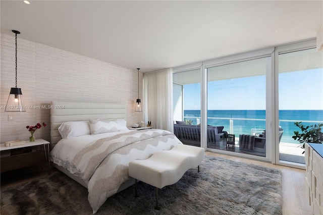 bedroom featuring access to exterior, wood-type flooring, a water view, and multiple windows