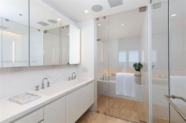 bathroom featuring vanity, a shower with shower door, and tasteful backsplash