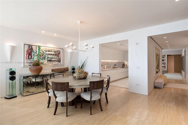 dining space with light hardwood / wood-style floors and a notable chandelier