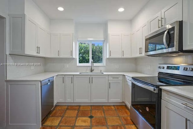 kitchen featuring decorative backsplash, appliances with stainless steel finishes, dark tile patterned floors, sink, and white cabinets