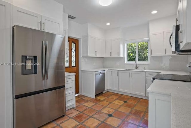 kitchen with sink, white cabinetry, stainless steel appliances, and tasteful backsplash