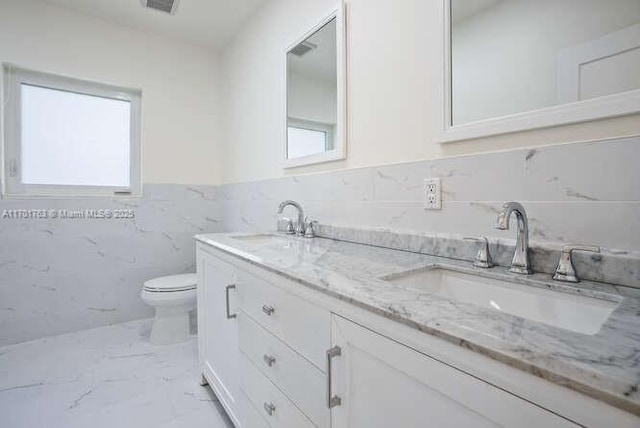 bathroom featuring vanity, toilet, and tile walls