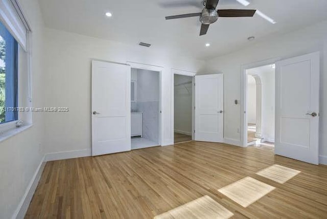 unfurnished bedroom featuring light hardwood / wood-style floors, ensuite bath, and ceiling fan