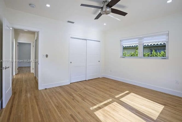 unfurnished bedroom featuring ceiling fan, a closet, and hardwood / wood-style flooring