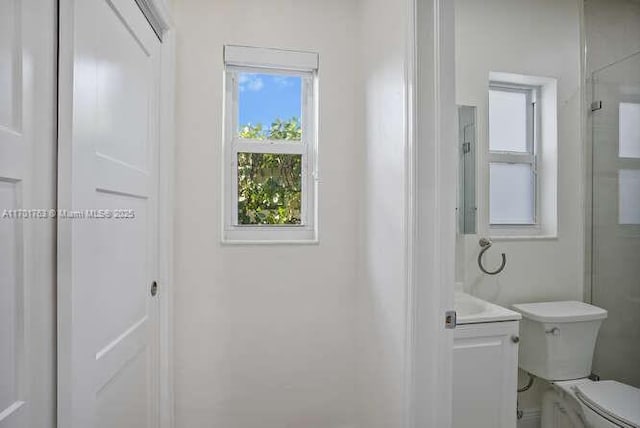 bathroom featuring vanity, toilet, and a shower with shower door