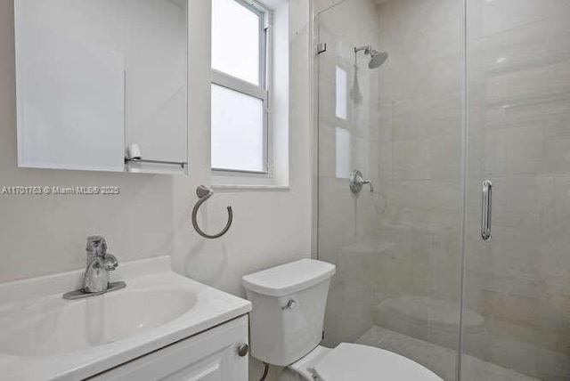 bathroom with vanity, a shower with shower door, and toilet