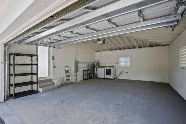 garage featuring water heater, washer and clothes dryer, and a garage door opener