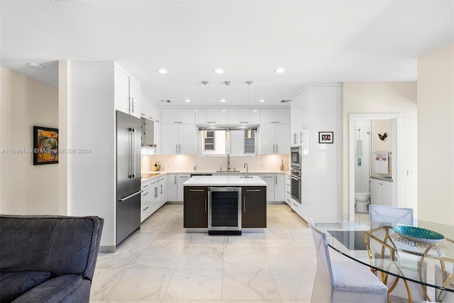 kitchen featuring wine cooler, an island with sink, pendant lighting, high quality fridge, and white cabinets