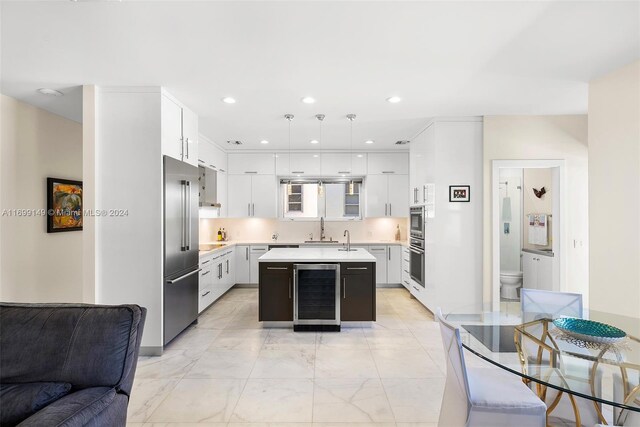 511 Madeira Ave, Coral Gables, FL 33134 - kitchen featuring beverage cooler, stainless steel built in fridge, open floor plan, light countertops, and a center island with sink