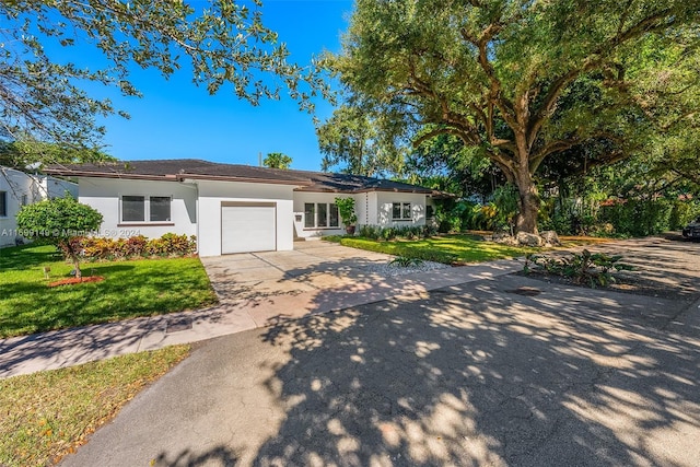 511 Madeira Ave, Coral Gables, FL 33134 - ranch-style house with driveway, stucco siding, an attached garage, and a front lawn
